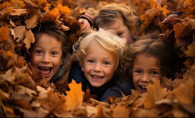 “Four children laughing and playing in a pile of autumn leaves.