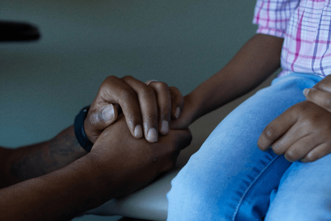 Close‑up of a child’s hand resting in father’s hands, showing a quiet moment of comfort between father and child.